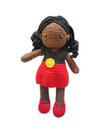 Suzie's Sunshine Dolls Alinta, a crochet doll with black curly hair, wearing a red dress and black top inspired by the Aboriginal flag.