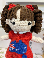 Suzie's Sunshine Dolls Mia, a crocheted doll with long brown hair in pigtails, wearing a red dress with an Australia flag appliqué.