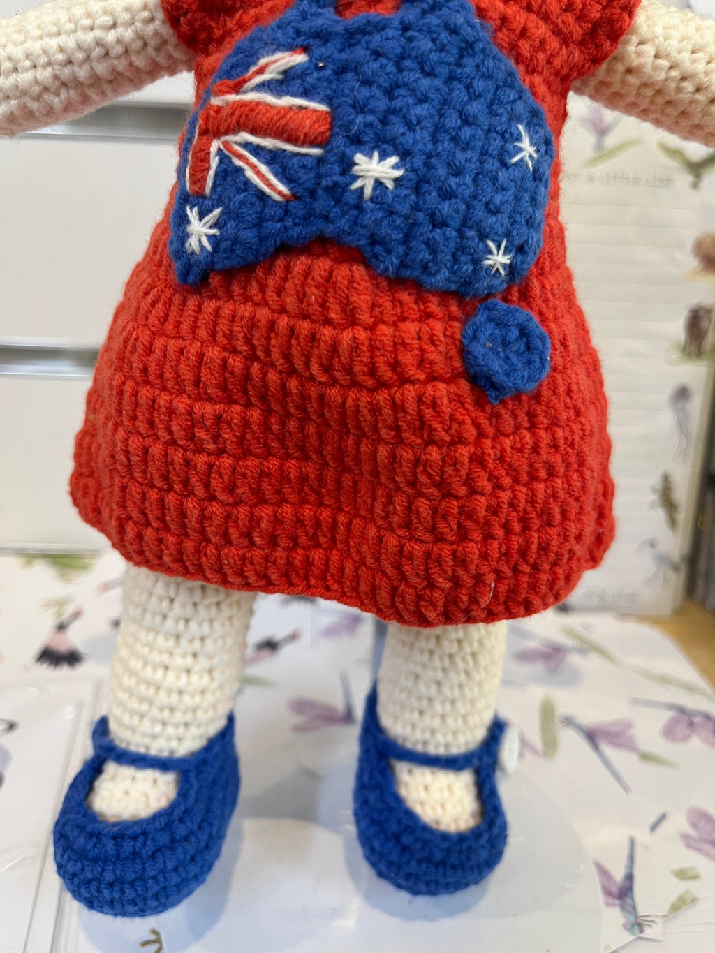 Suzie's Sunshine Dolls Mia, a crocheted doll with long hair, wearing a red dress with Australia flag appliqué and blue shoes.