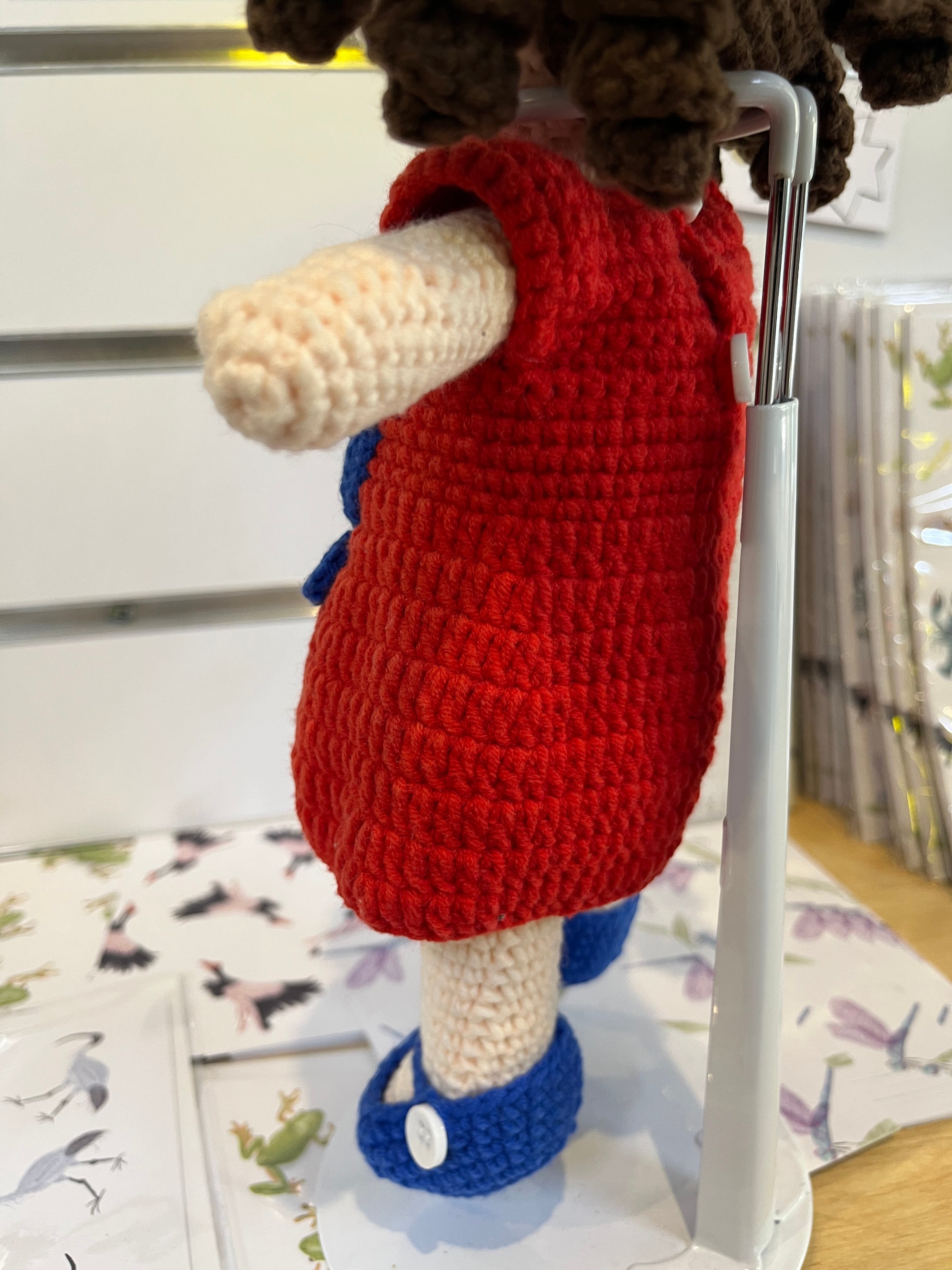 Suzie's Sunshine Dolls Mia, a crocheted doll with long brown hair, wearing a red dress with blue Australian flag detail and blue shoes.