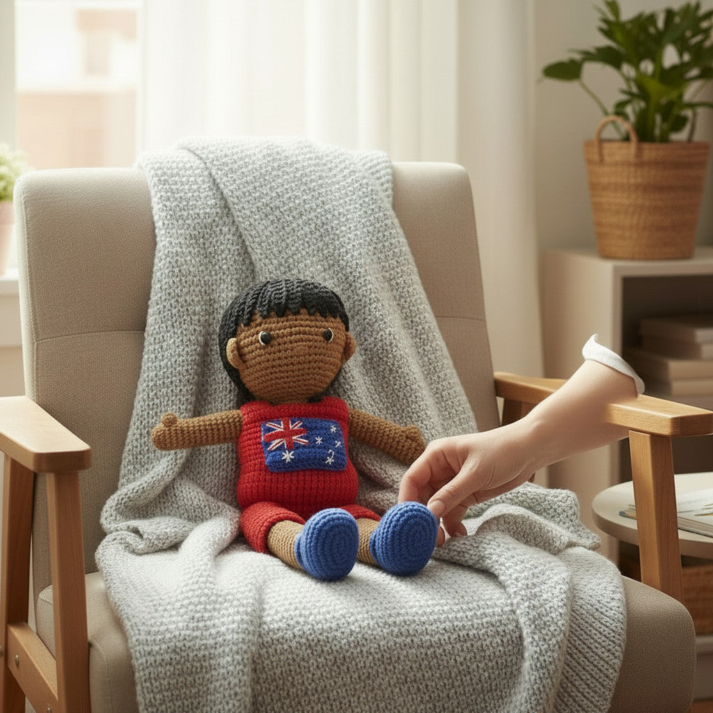 Suzie's Sunshine Dolls Jack, a crocheted doll with short black hair, wearing a red outfit with the Australian flag on the chest and blue shoes.