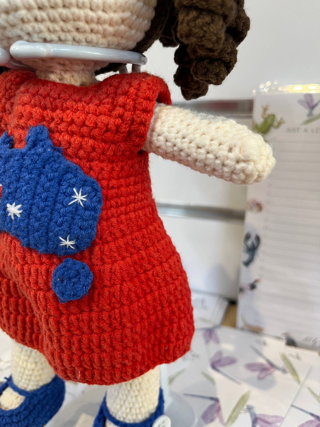 Suzie's Sunshine Dolls Mia, a crocheted doll with long brown hair, wearing a red dress with Australia flag applique and blue shoes.