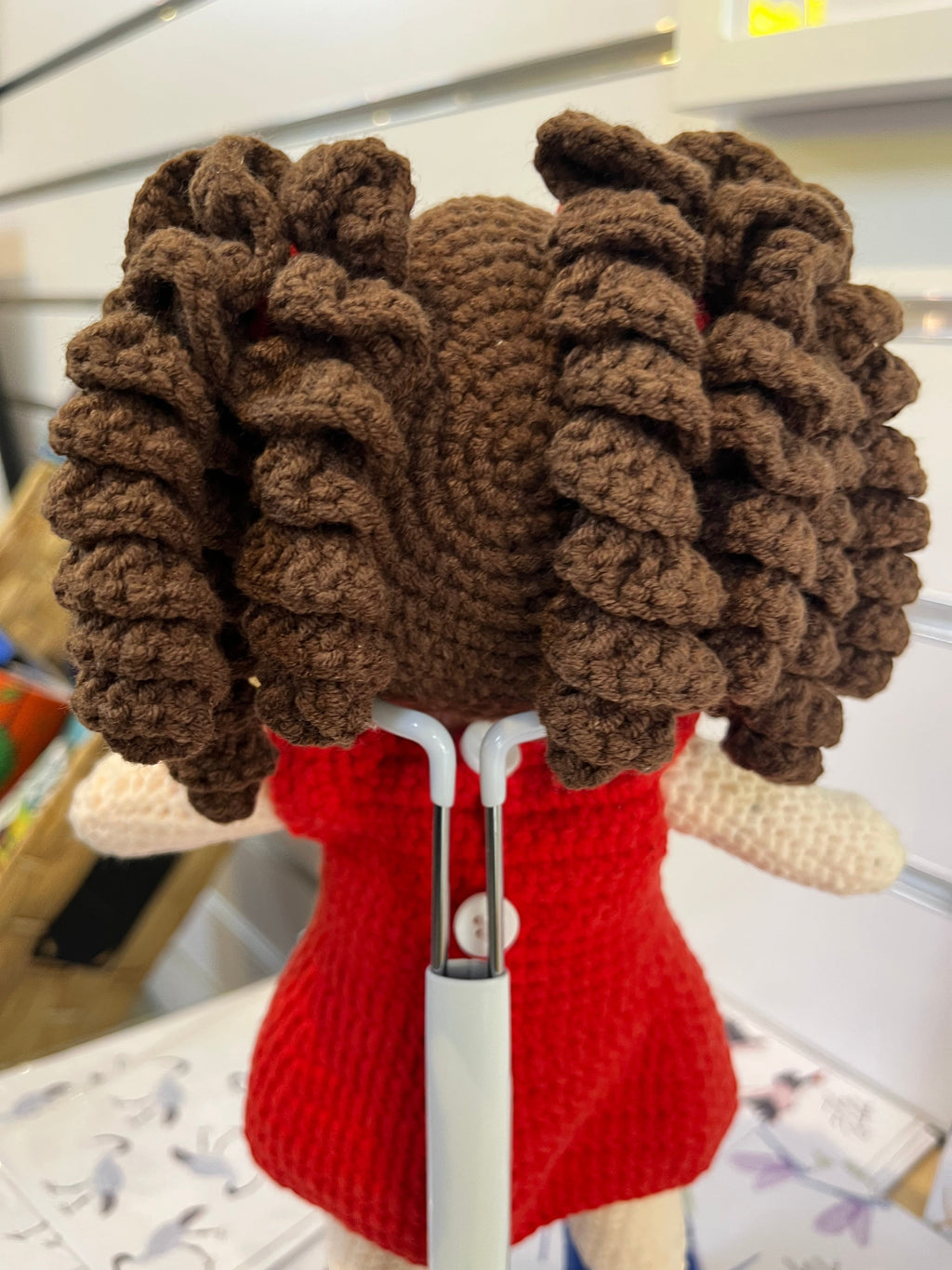 Suzie's Sunshine Dolls Mia, a crocheted doll with long brown curly hair, wearing a red dress with an Australian flag applique.