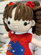 Suzie's Sunshine Dolls Mia, a crocheted doll with long brown hair in pigtails, wearing a red dress with an Australian flag appliqué.