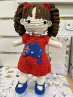 Suzie's Sunshine Dolls Mia, a crocheted doll with long brown hair in pigtails, wearing a red dress with an Australian flag appliqué and blue shoes.