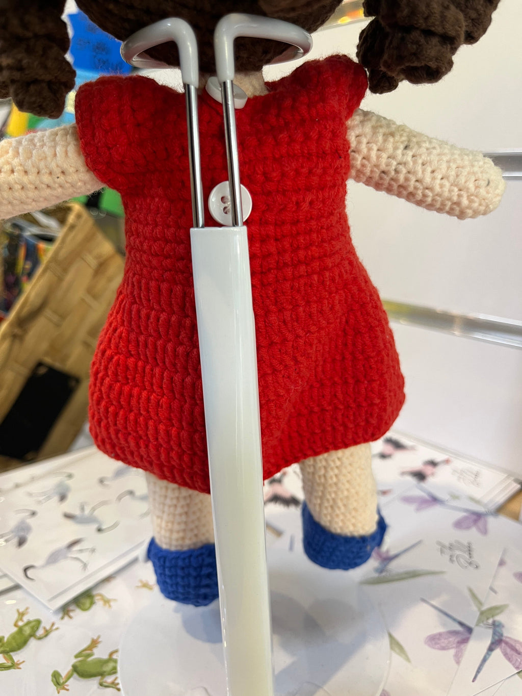 Suzie's Sunshine Dolls Mia, a crocheted doll with long brown hair, wearing a red dress with Australian flag detail and blue shoes.