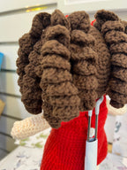 Suzie's Sunshine Dolls Mia, a crocheted doll with long brown curly hair, wearing a red dress with an Australian flag appliqué.