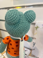 Suzie's Sunshine Dolls Calvin the Croc, a handmade teal crochet toy with an orange sweater and heart pattern.