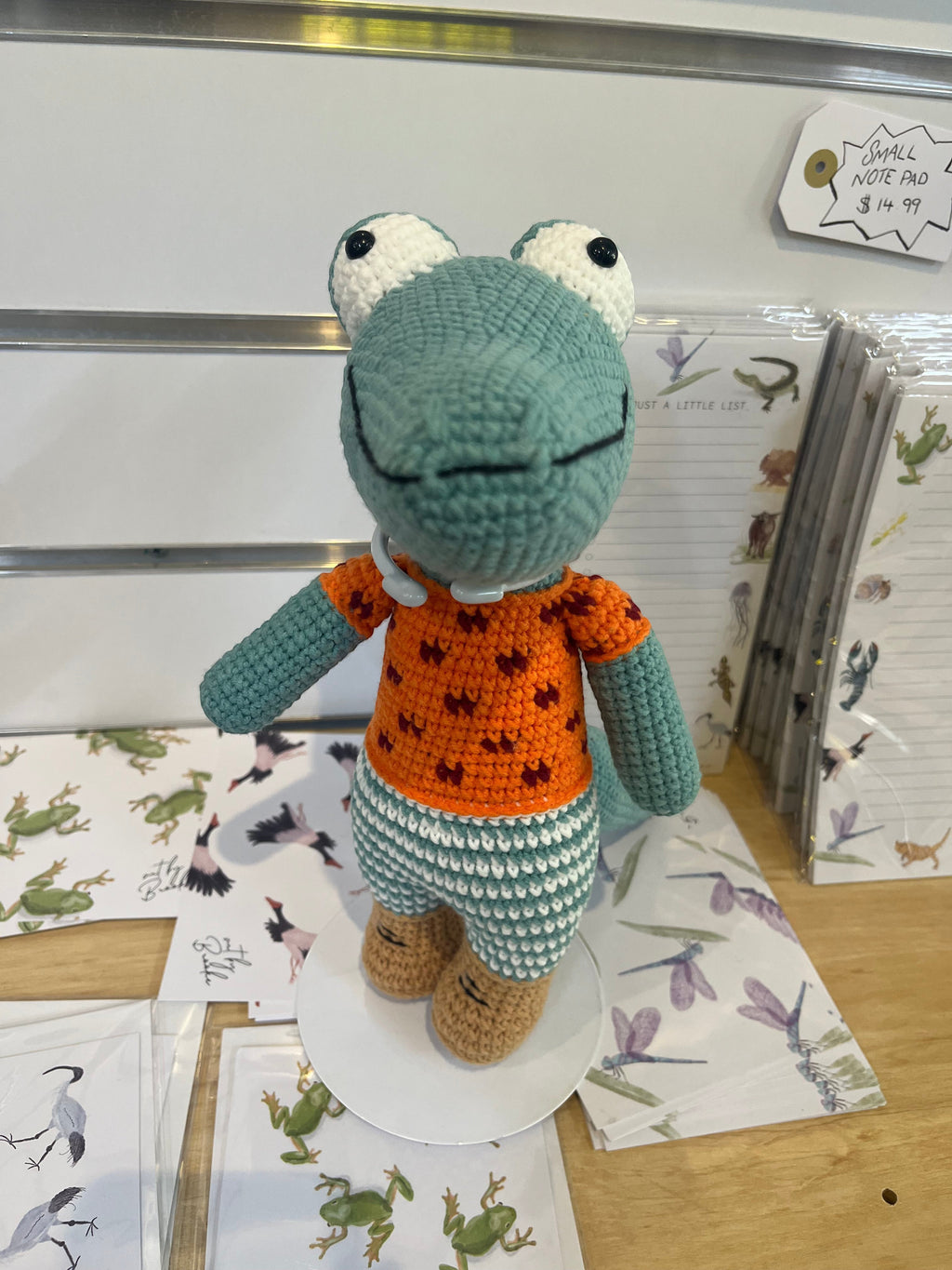 Suzie's Sunshine Dolls Calvin the Croc, a handmade crochet toy with a teal body, orange shirt, and patterned shorts.