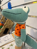 Suzie's Sunshine Dolls Calvin the Croc, a handmade crochet toy with a teal body, orange shirt, and white and teal striped pants.