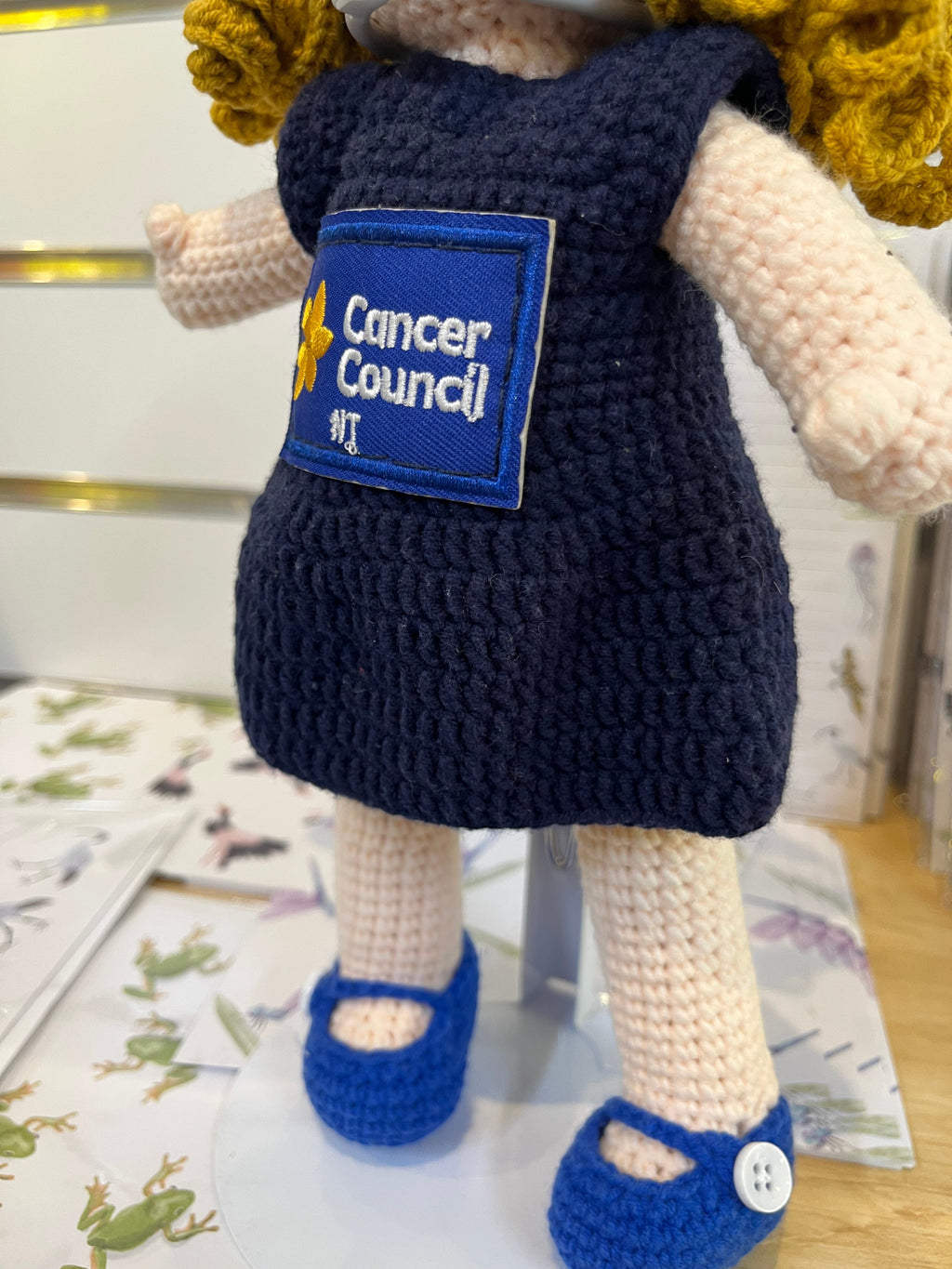 Suzie's Sunshine Dolls navy crocheted doll with Cancer Council NT patch and blue shoes. Yarn doll.