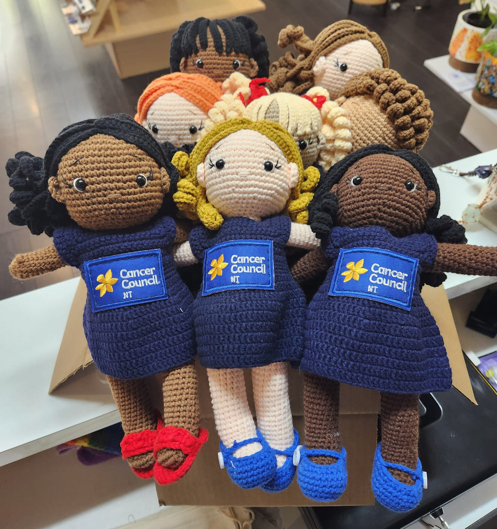 Suzie's Sunshine Dolls: Hand-crocheted navy dolls with Cancer Council NT patch, representing courage and support.