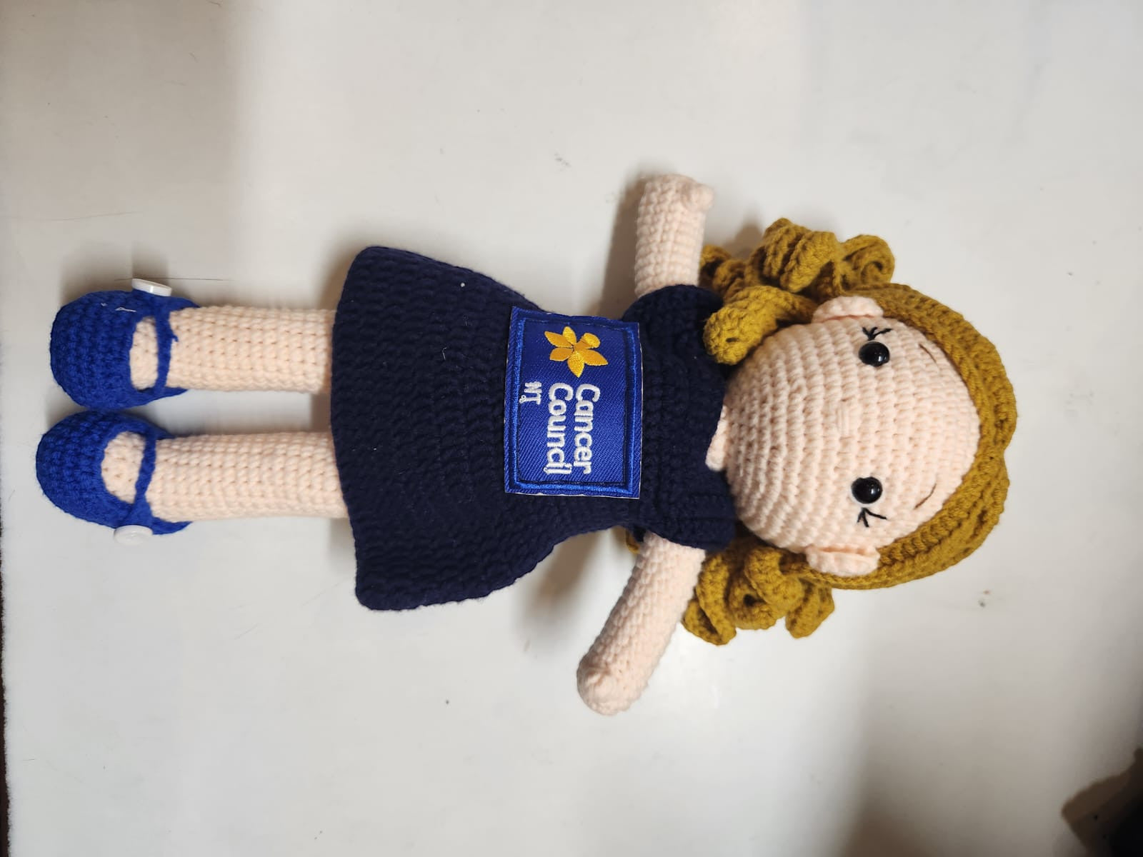 Suzie's Sunshine Dolls navy crocheted doll with Cancer Council NT patch and blue shoes. Educational toy.