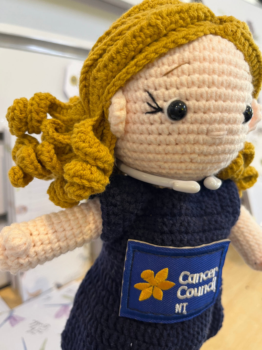 Suzie's Sunshine Dolls navy crocheted doll with blonde hair and Cancer Council NT patch. Educational toy.