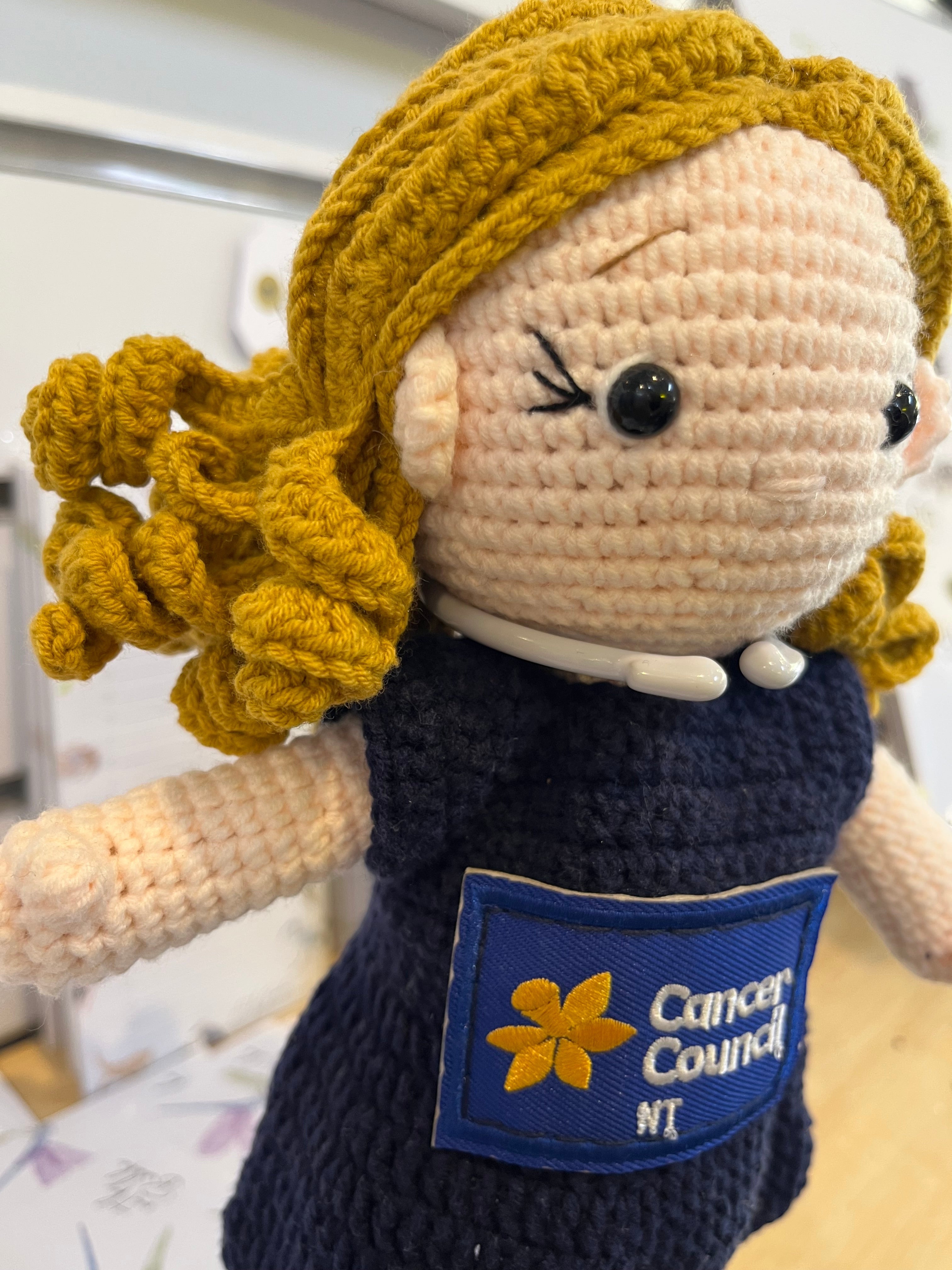 Suzie's Sunshine Dolls navy crocheted doll with blonde hair and Cancer Council NT patch. Educational toy.