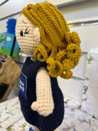 Suzie's Sunshine Dolls hand-crocheted navy doll with yellow yarn hair and Cancer Council NT patch. Educational and symbolic.