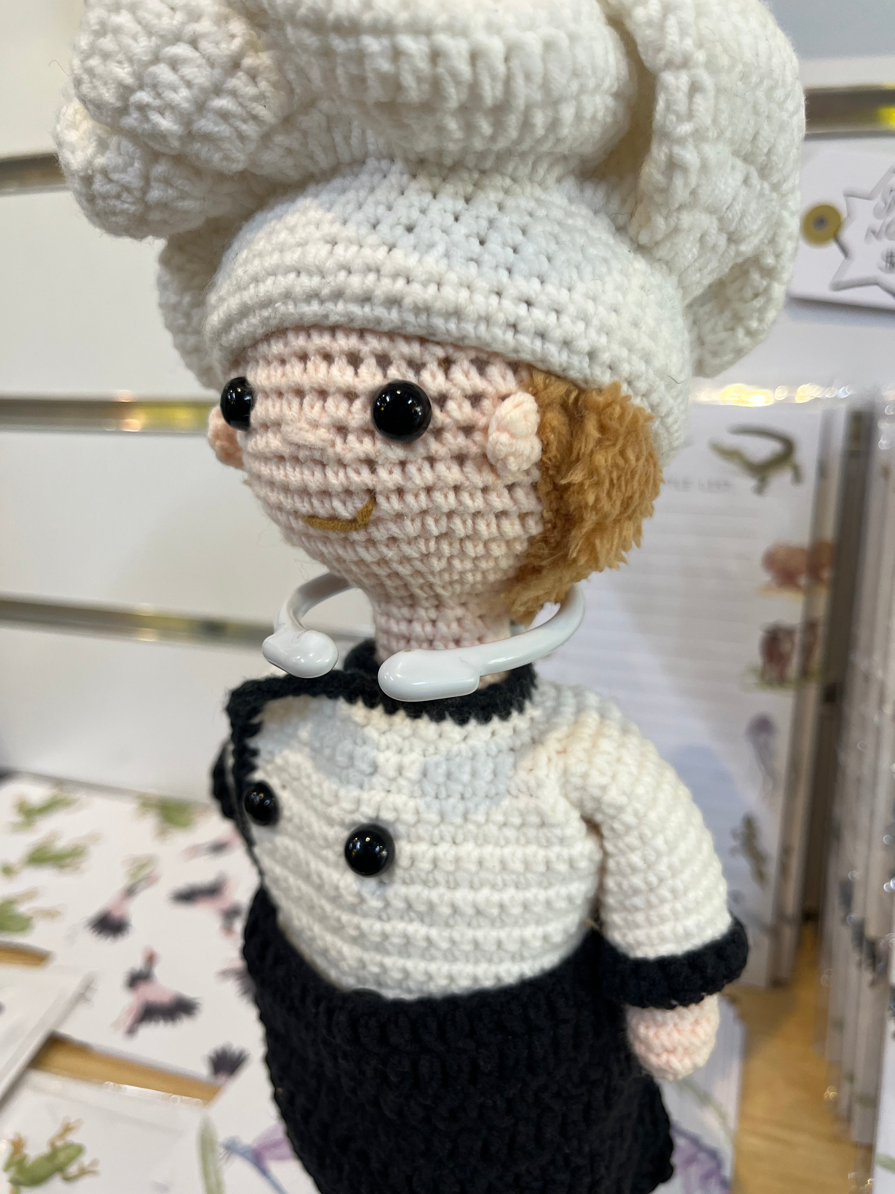 Suzie's Sunshine Dolls handcrafted crochet chef doll in white uniform, black apron, and tall hat. Perfect for play.