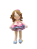 Suzie's Sunshine Dolls Cleo, a handmade crochet doll with brown yarn curls, wearing a pink, purple, and blue ruffled dress and blue shoes.