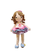 Suzie's Sunshine Dolls Cleo, a handmade crochet doll with brown yarn curls, wearing a pink, purple, and blue ruffled dress and blue shoes.