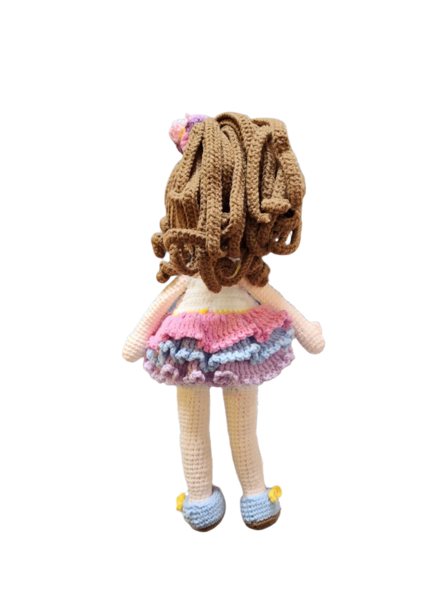 Suzie's Sunshine Dolls Cleo, a handmade crochet doll with brown curly hair, a pink, purple, and blue ruffled dress, and blue shoes.
