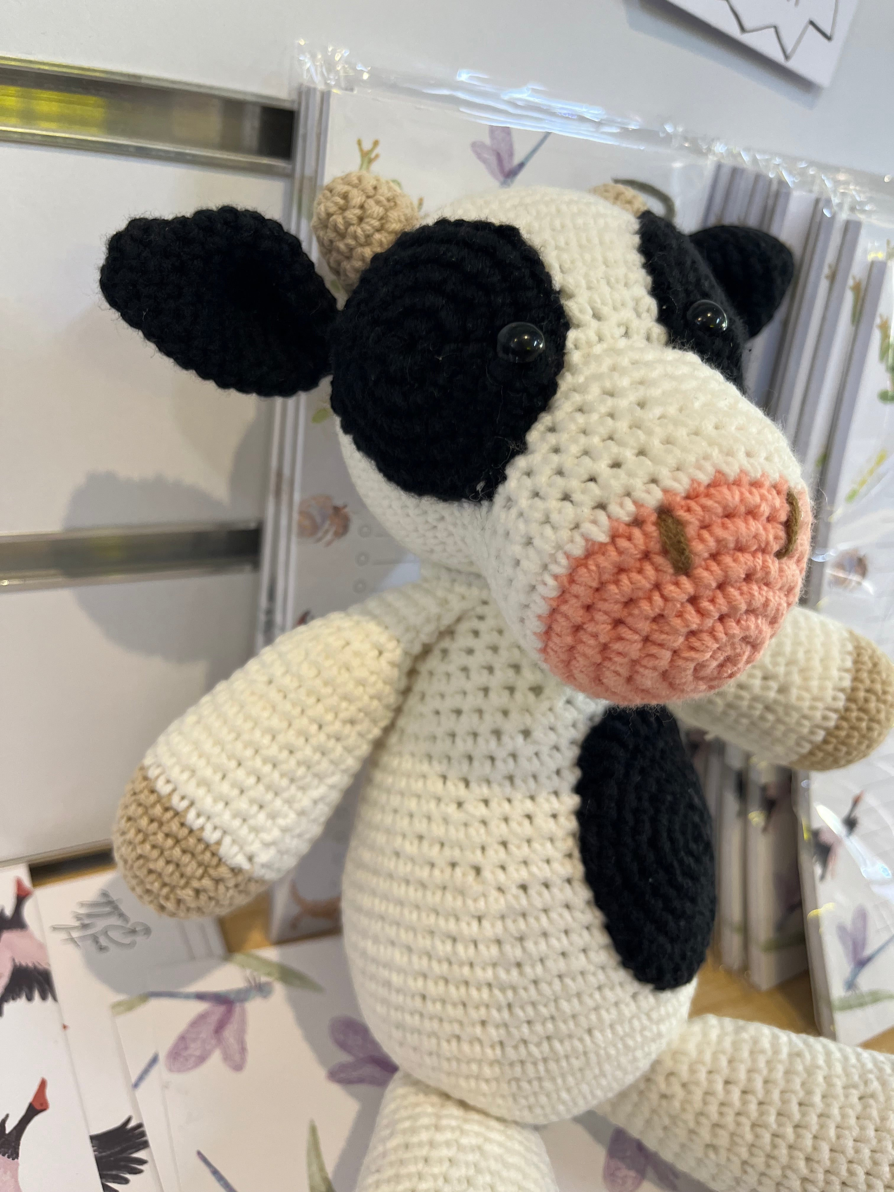 Suzie's Sunshine Dolls Daisy the Cow, a handmade crocheted toy with black and white patches, pink snout, and beige accents.