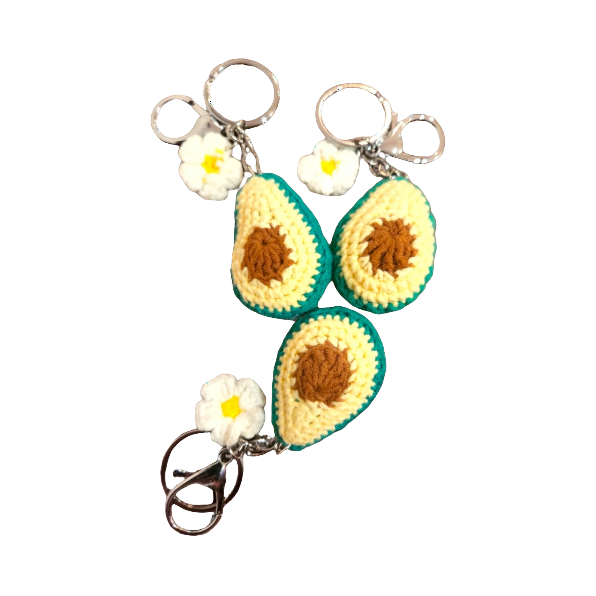 Suzie's Sunshine Dolls handmade crochet avocado keychains with white flowers and metal clasps. Yellow, brown, and green yarn.