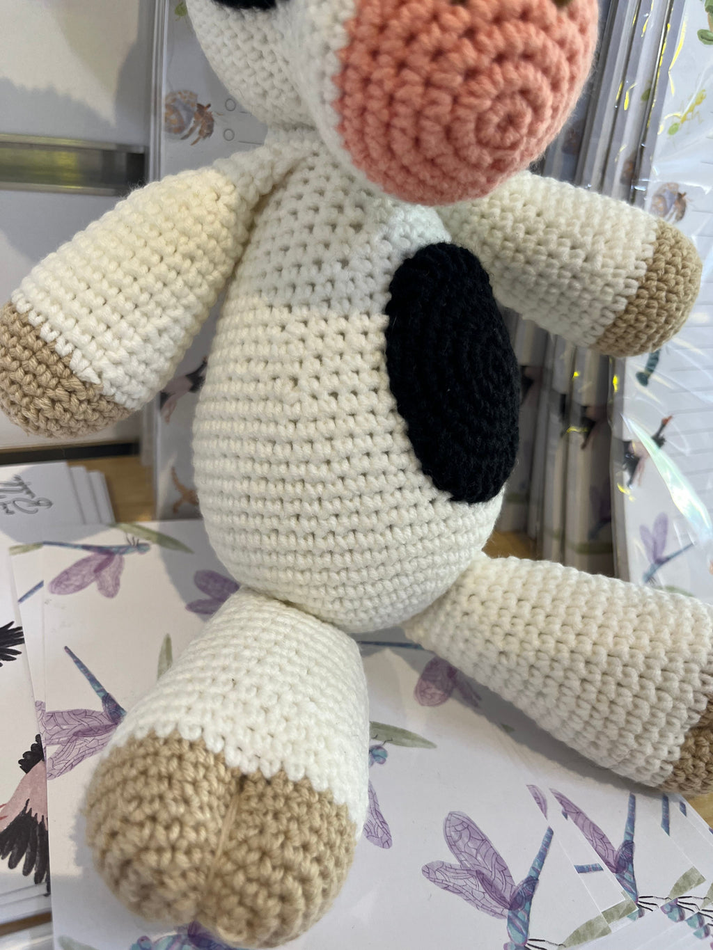 Suzie's Sunshine Dolls Daisy the Cow, a handmade crochet toy with black and white spots, pink snout, and beige hooves.