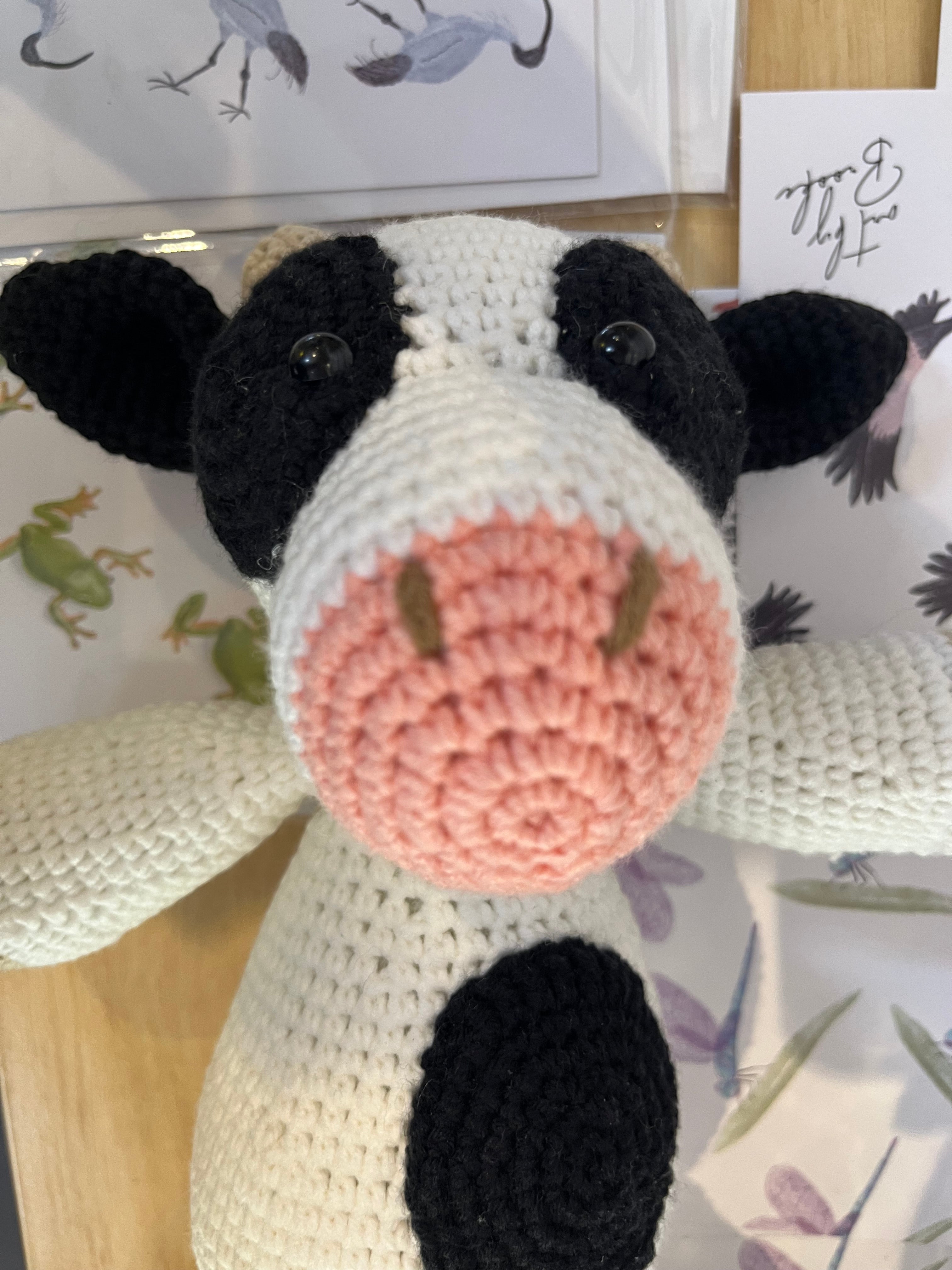 Suzie's Sunshine Dolls Daisy the Cow, a handmade crochet toy with black and white patches, pink snout, and black button eyes.