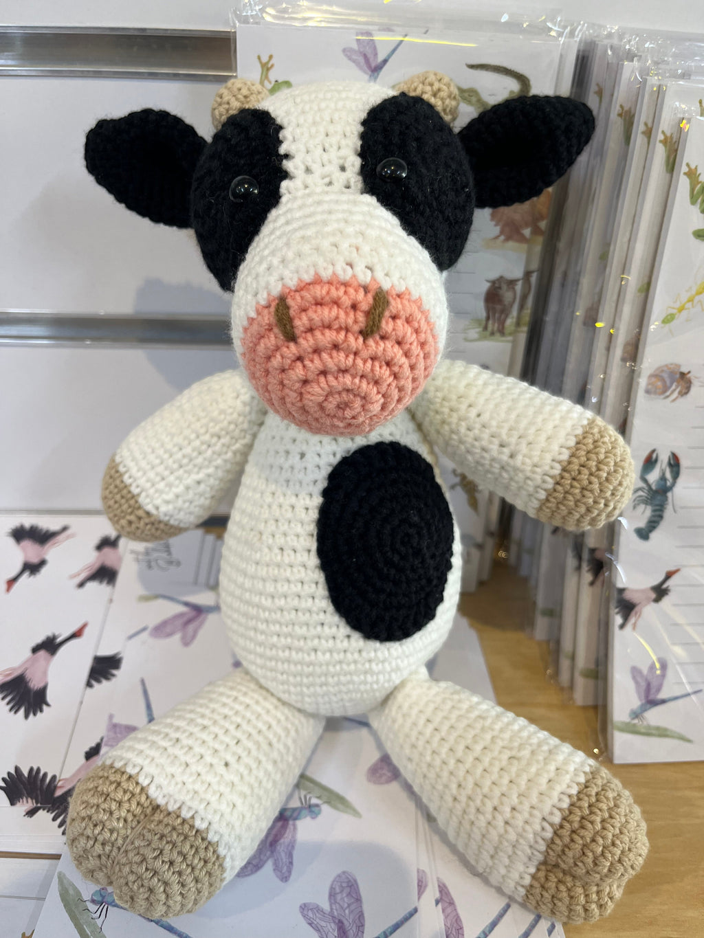 Suzie's Sunshine Dolls Daisy the Cow, a handmade crochet toy with black and white spots, pink snout, and beige hooves.