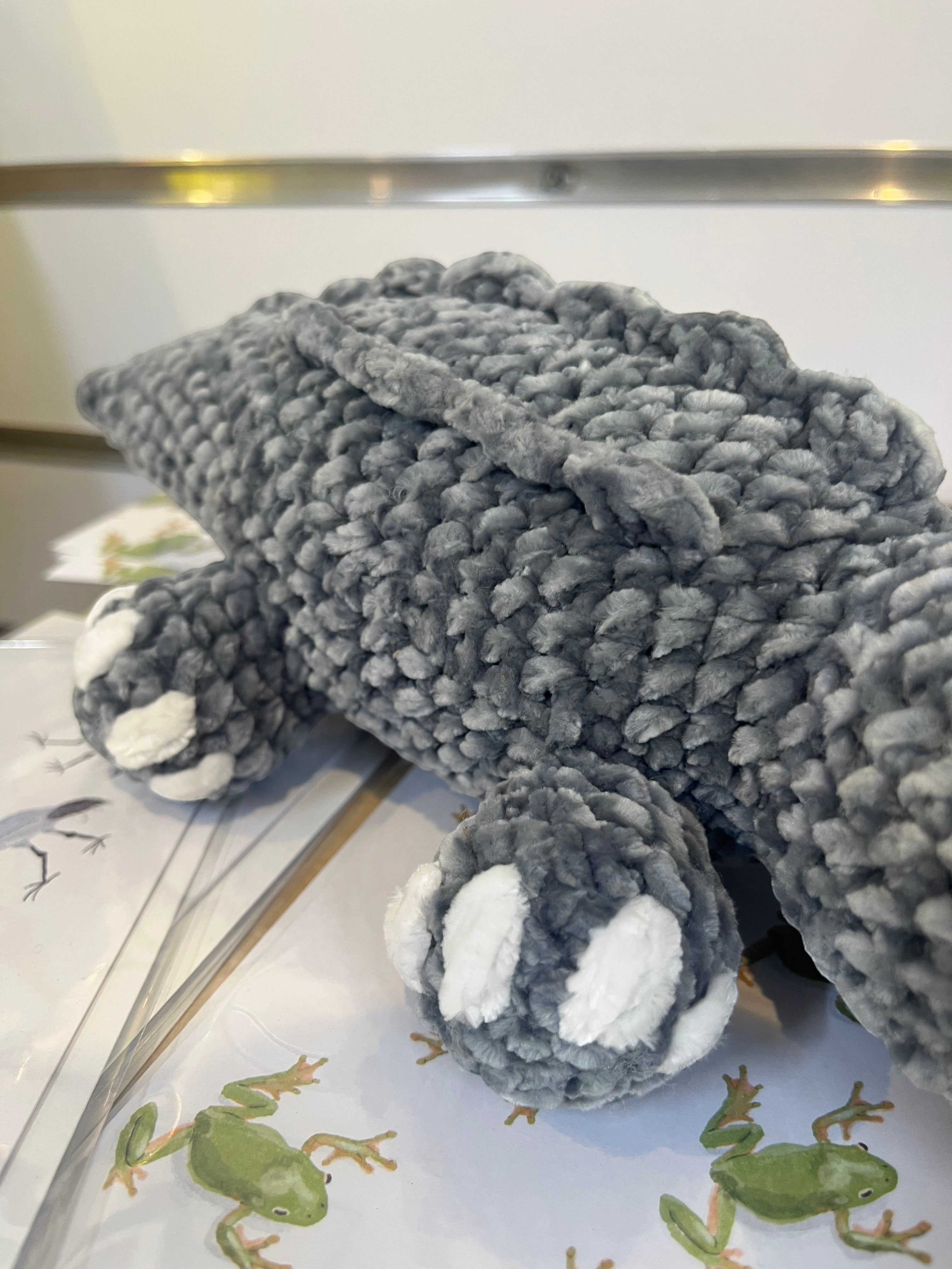 Suzie's Sunshine Dolls Kurtis the Croc, a soft grey crocheted crocodile plush toy with white toes and a stitched smile.