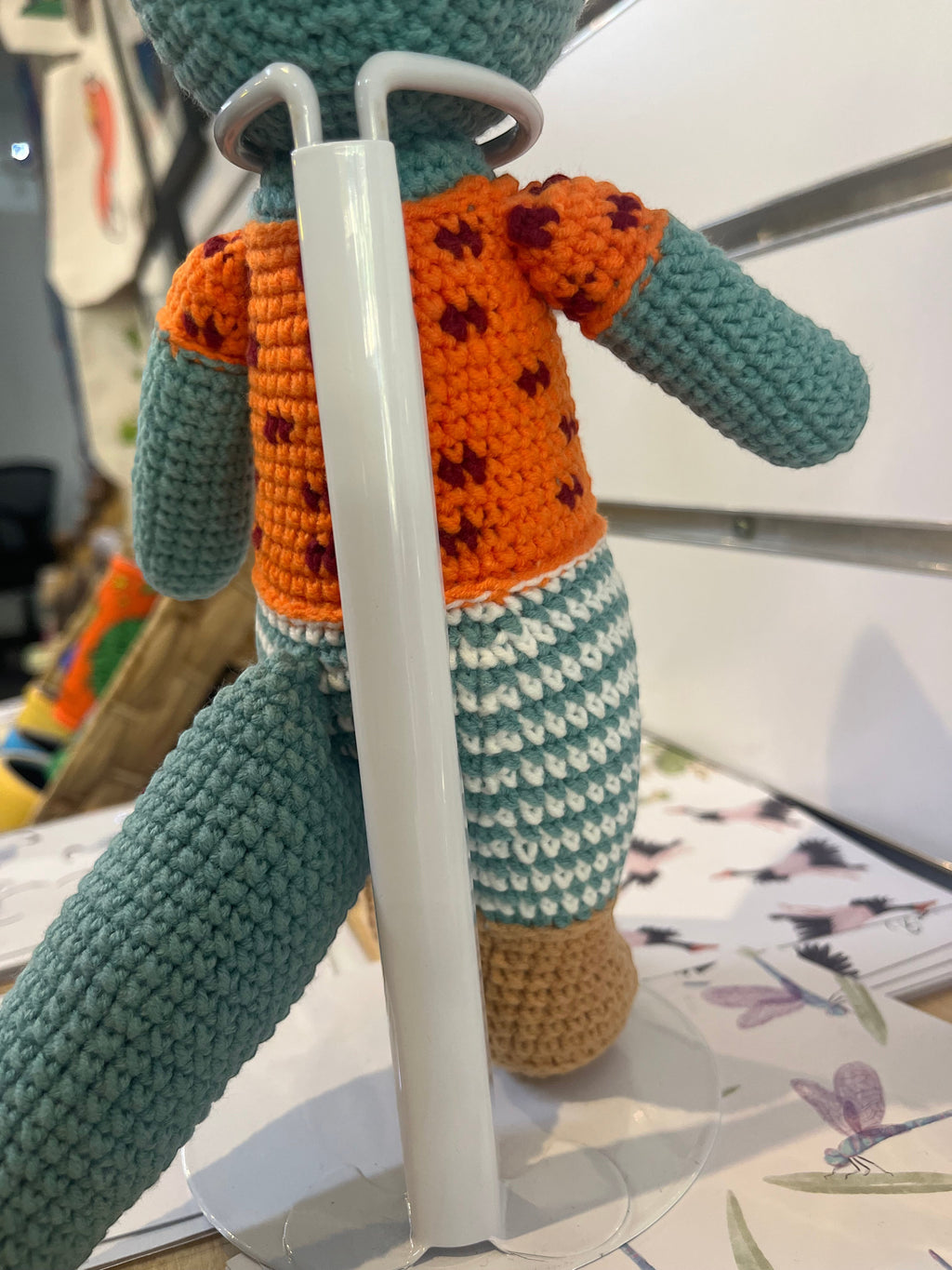 Suzie's Sunshine Dolls Calvin the Croc handmade crochet doll, teal body, orange shirt with maroon spots, striped shorts.