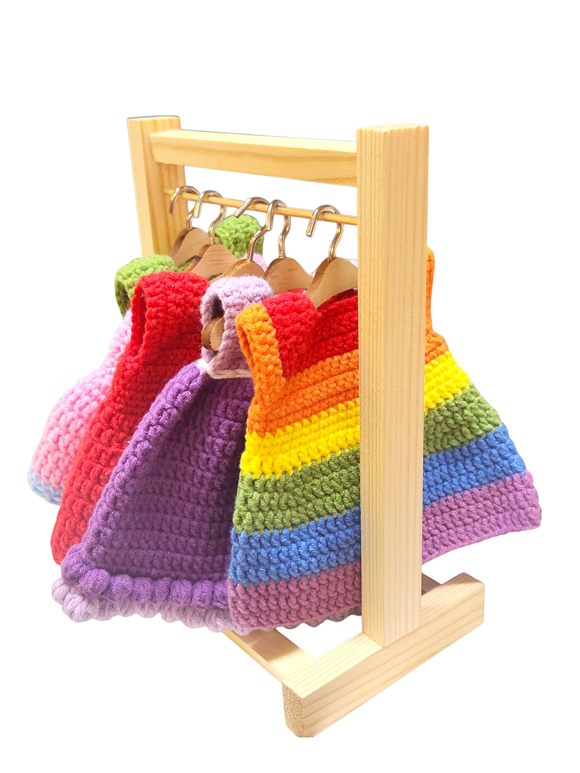 Suzie's Sunshine Dolls handmade crochet doll clothes in rainbow and solid colors on a wooden rack.