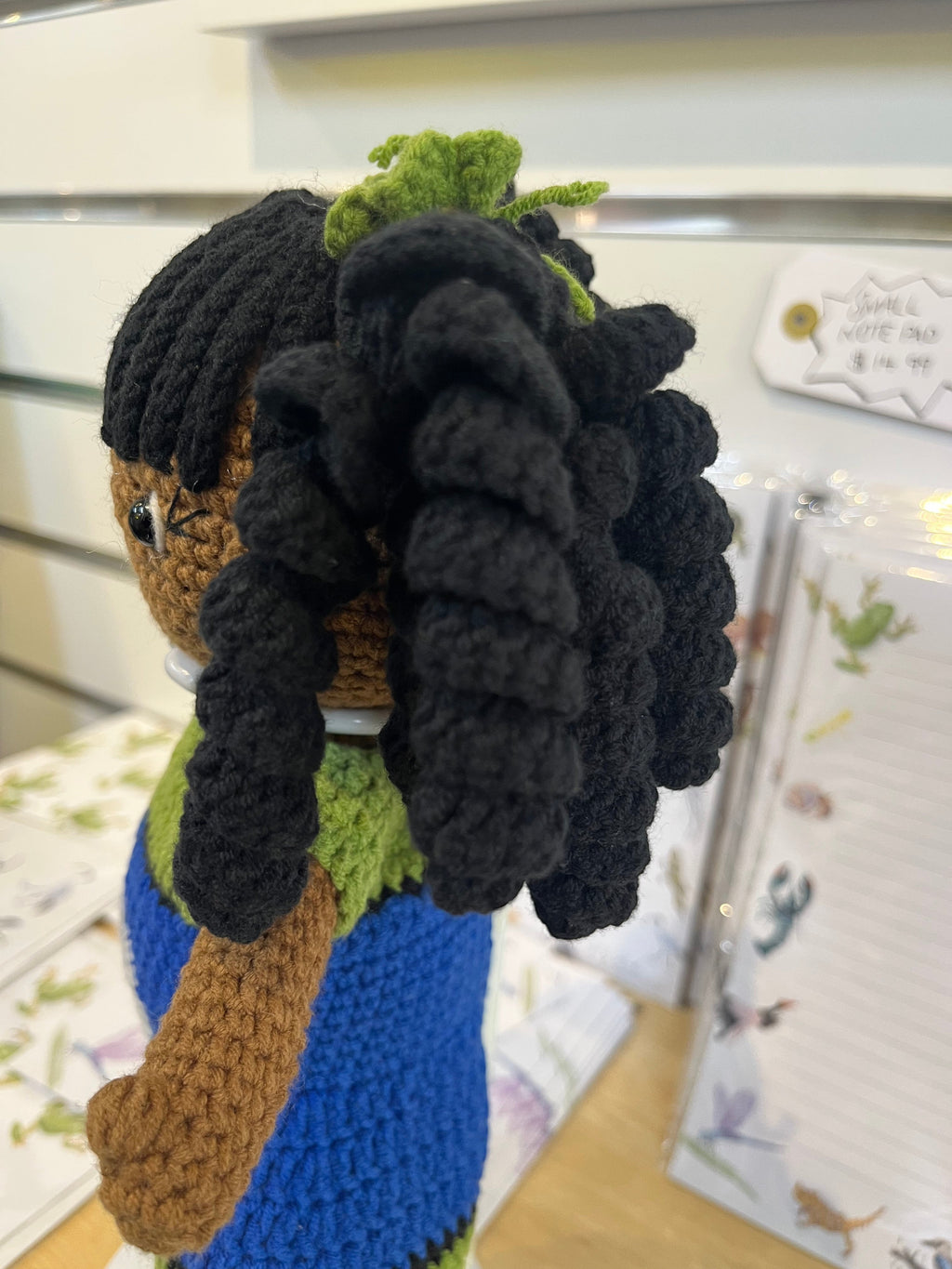 Suzie's Sunshine Dolls handmade crochet doll with long black curly hair and a blue, green, and black dress.