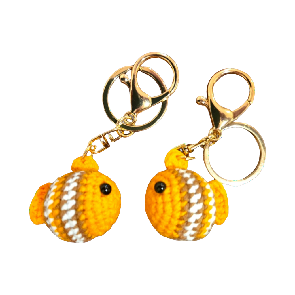Suzie's Sunshine Dolls handmade crochet fish keychains in orange, white, and brown yarn with gold clasps.