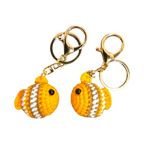 Suzie's Sunshine Dolls handmade crochet fish keychains in orange, white, and brown yarn with gold clasps.