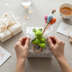 Suzie's Sunshine Dolls green crocheted Kitty the Croc pram toy with pastel balloons and wooden rattle clip.