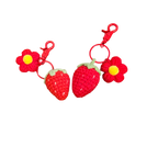Suzie's Sunshine Dolls handmade crochet strawberry and flower keychains, red yarn with green leaves and yellow center.