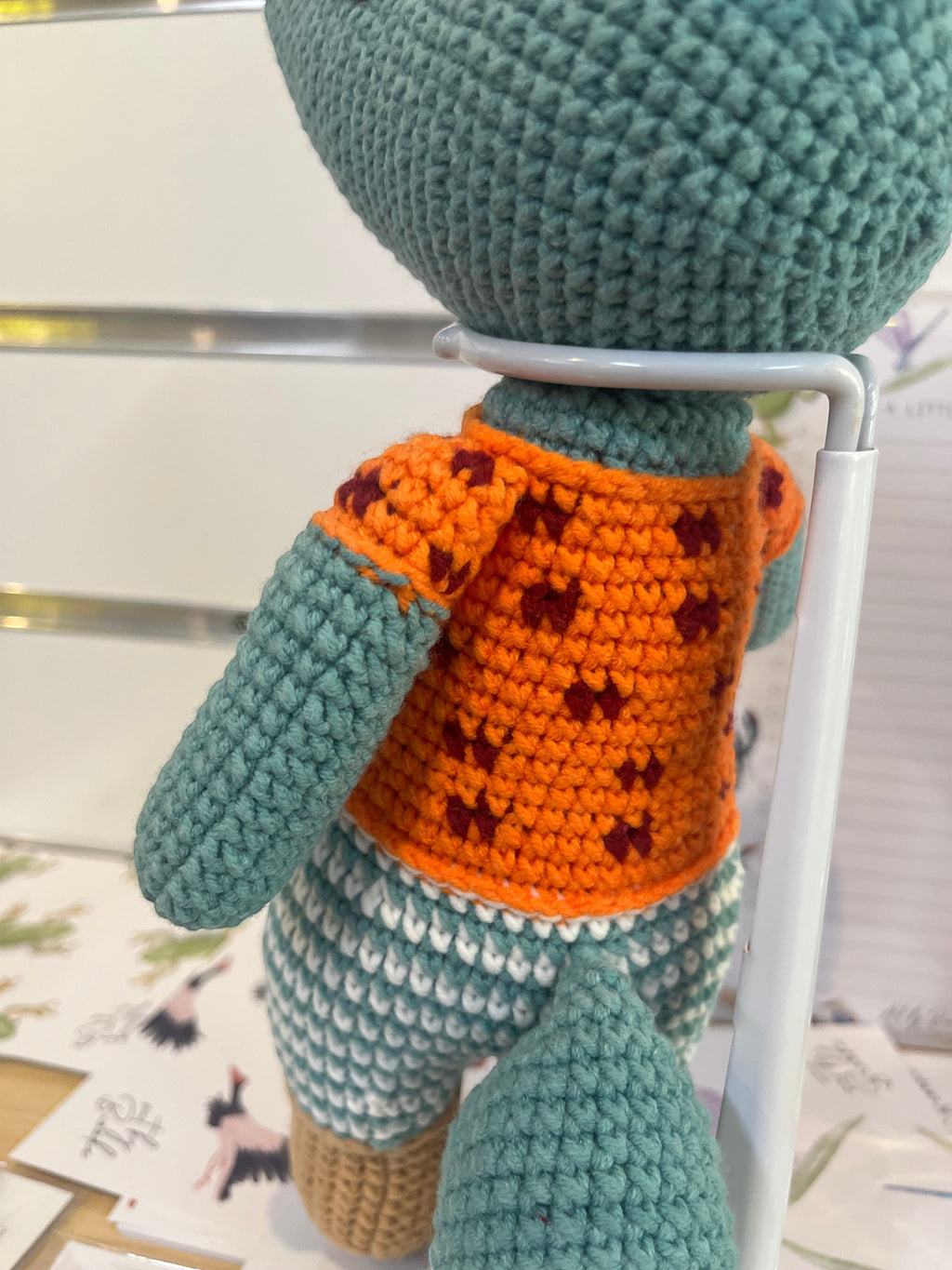 Suzie's Sunshine Dolls Calvin the Croc, a handmade crochet toy in teal with an orange patterned shirt and teal & white striped shorts.