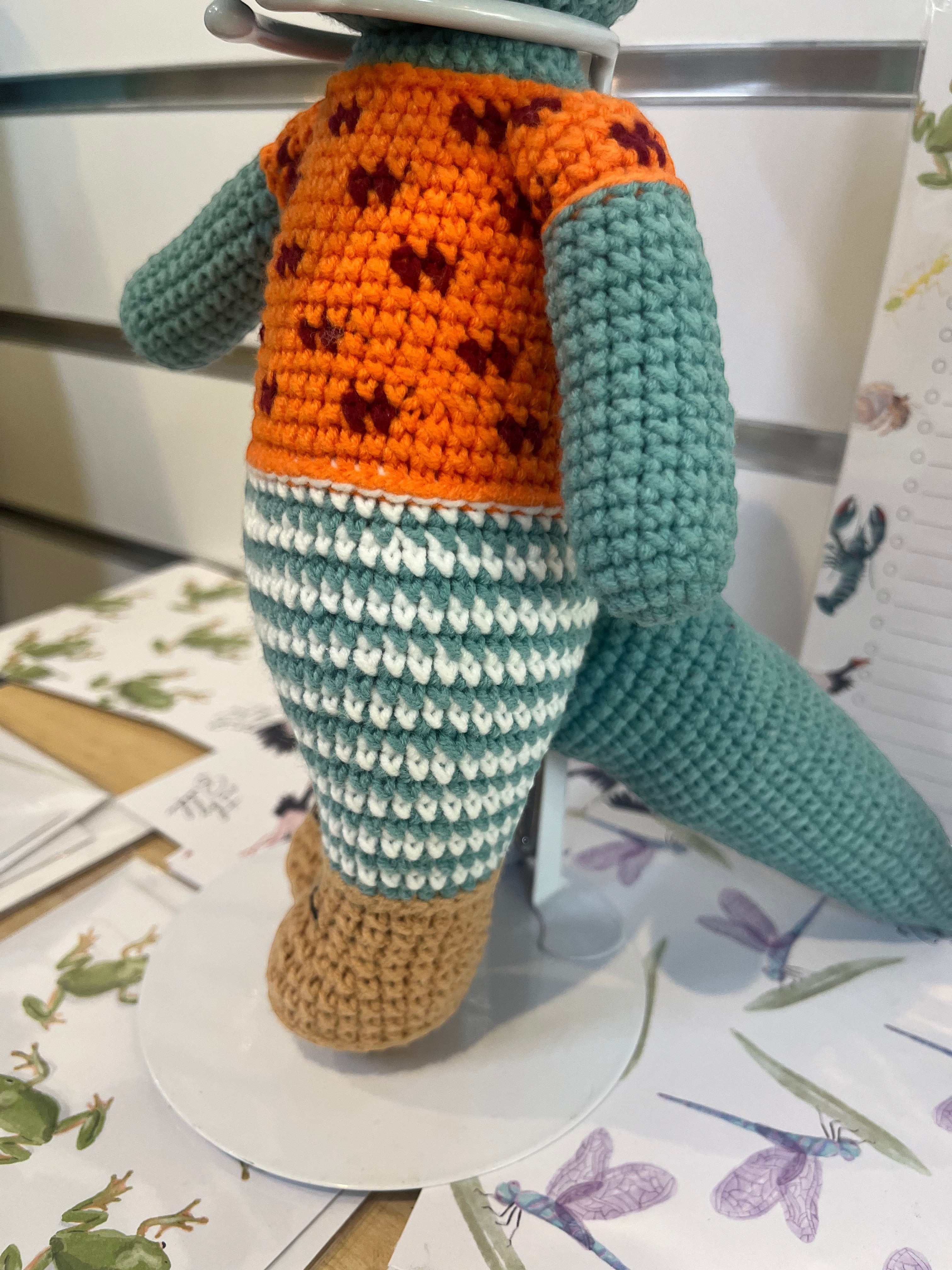 Suzie's Sunshine Dolls Calvin the Croc, a handmade crochet toy in teal with an orange shirt and striped pants.