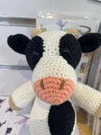 Suzie's Sunshine Dolls handmade crocheted cow toy with black and white spots, pink snout, and beige horns.