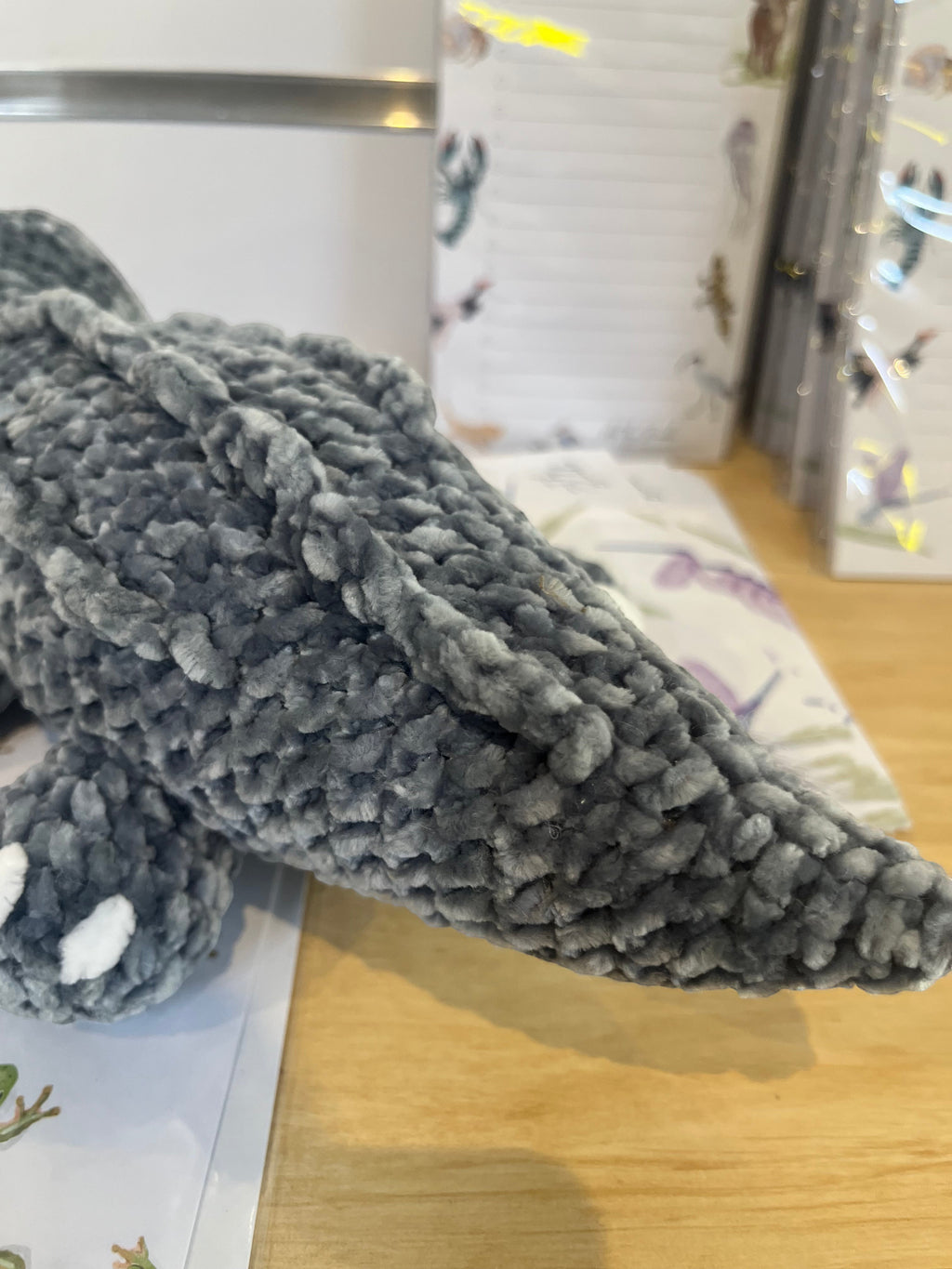 Suzie's Sunshine Dolls Kurtis the Croc, a grey crocheted plush toy with white toes and a stitched smile.