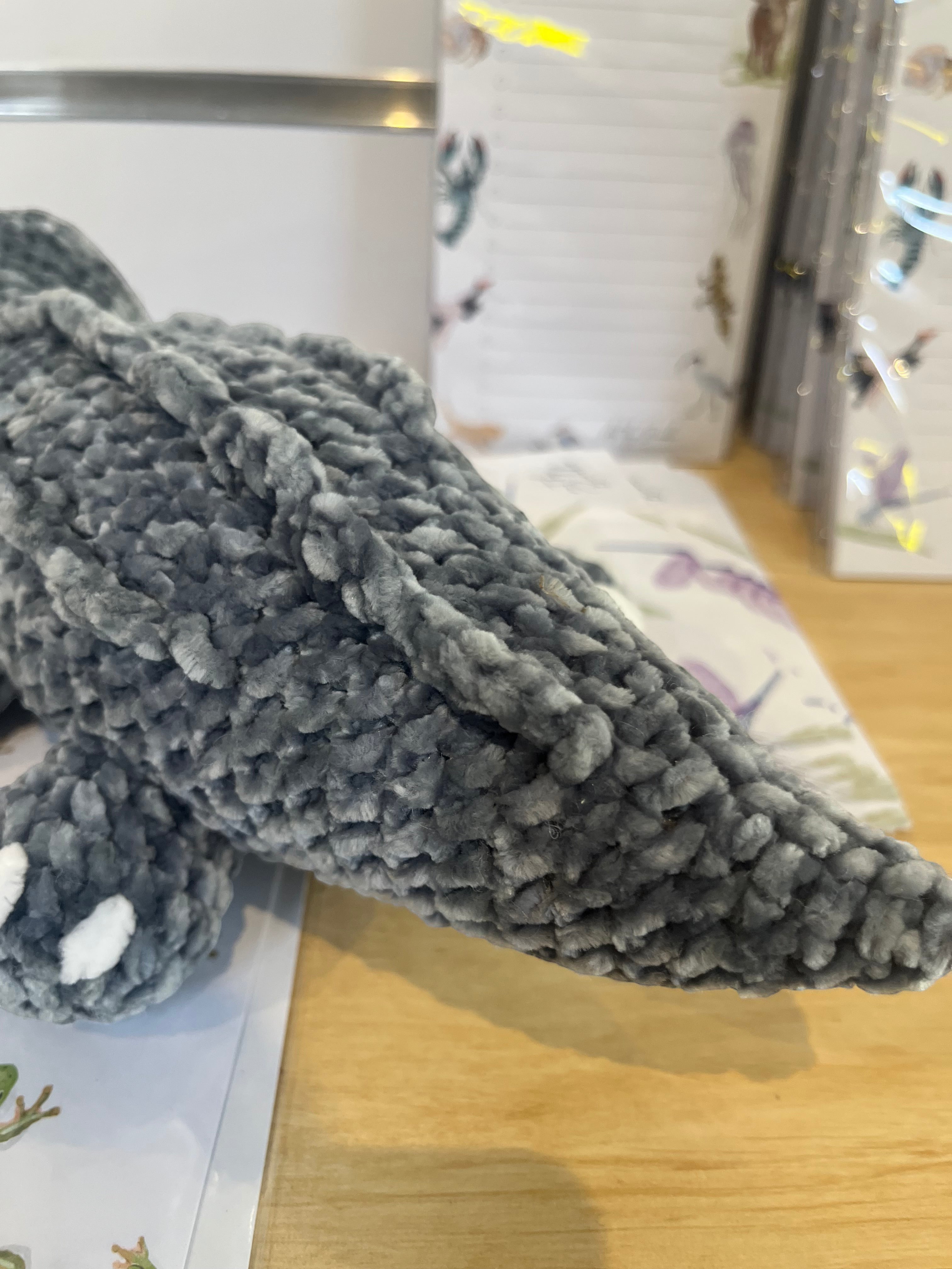 Suzie's Sunshine Dolls Kurtis the Croc, a grey crocheted plush toy with white toes and a stitched smile.