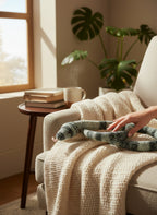 Suzie's Sunshine Dolls hand-crocheted snake toy in green and black stripes, with a pink tongue, resting on a cream blanket.