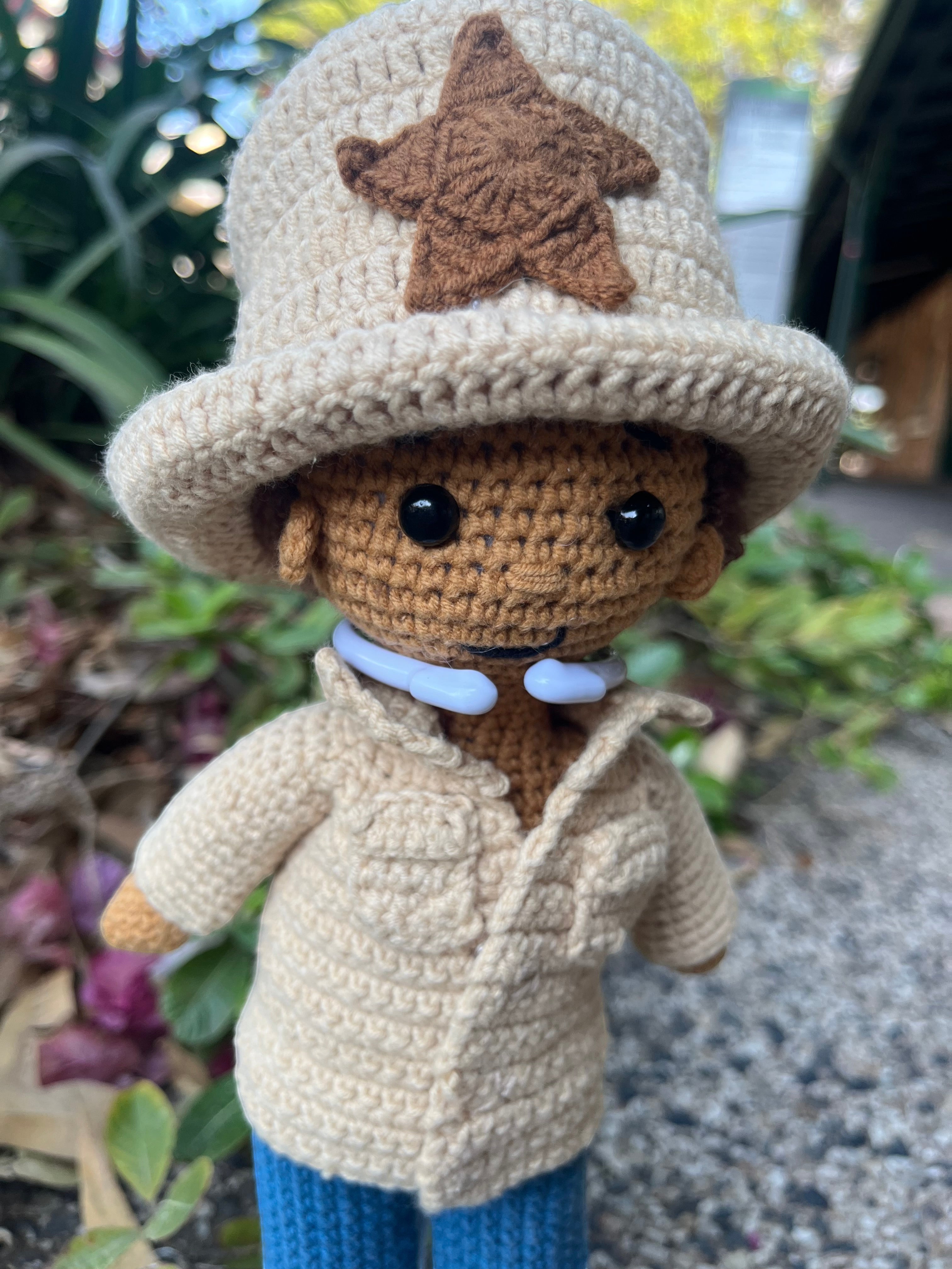 Suzie's Sunshine Dolls handmade crocheted doll with a tan hat featuring a brown star, tan jacket, and blue pants.