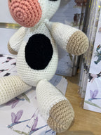 Suzie's Sunshine Dolls Daisy the Cow, a handmade crocheted toy with black and white patches, pink snout, and beige hooves.