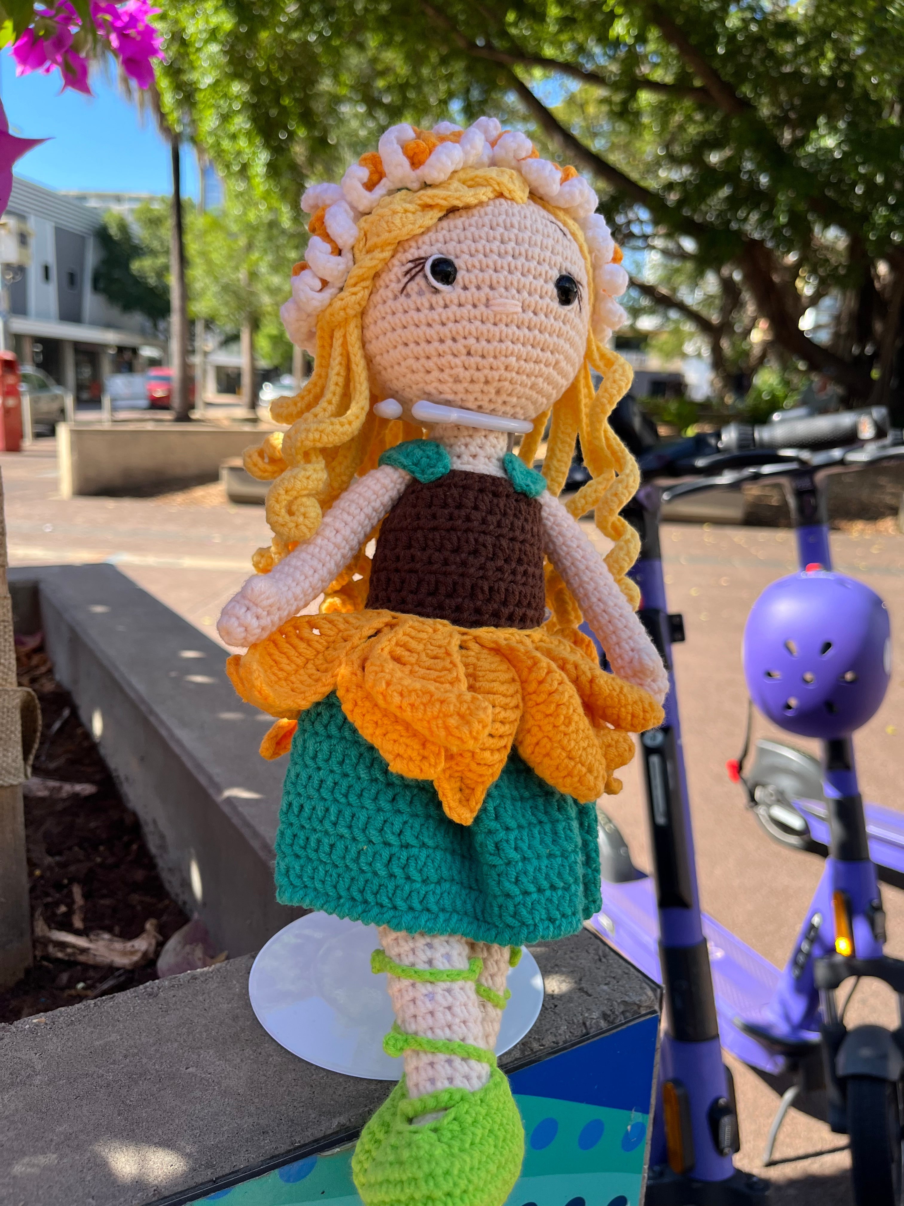 Suzie's Sunshine Dolls Daisy crochet doll with blonde yarn hair, sunflower skirt, green shoes, and floral crown.