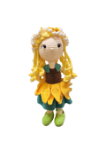 Suzie's Sunshine Dolls Daisy, a crocheted doll with golden yarn hair, wearing a sunflower skirt, green shoes, and a floral crown.