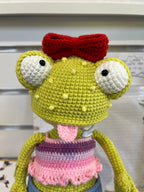 Suzie's Sunshine Dolls Frieda the Frog crochet doll with googly eyes, red bow, pink tongue out, and striped top.