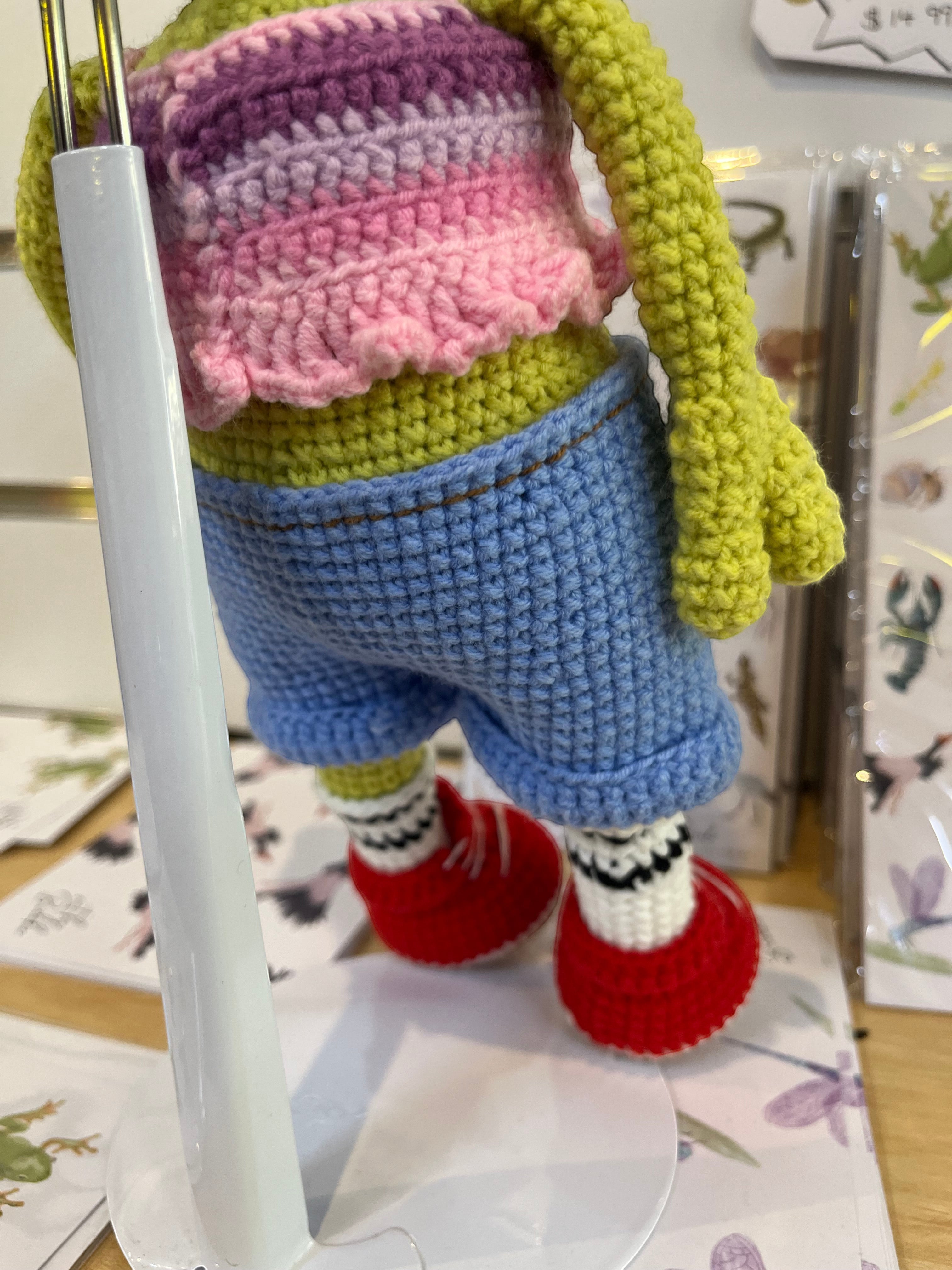 Suzie's Sunshine Dolls Frieda the Frog crochet doll in pastel crop top, denim shorts, red sneakers, and striped socks.