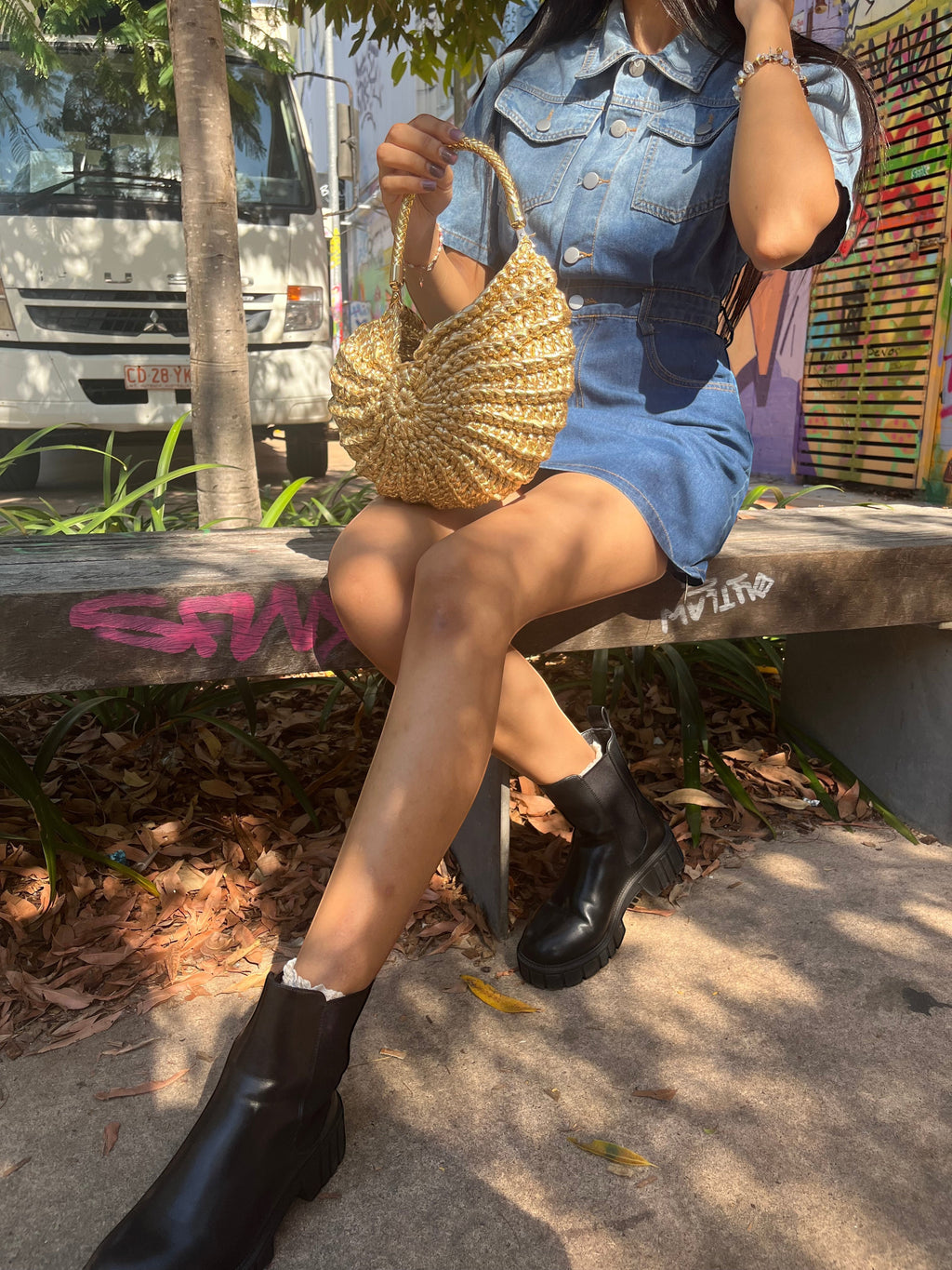 Suzie's Sunshine Dolls gold woven shell-shaped handbag with braided handle, textured metallic material.